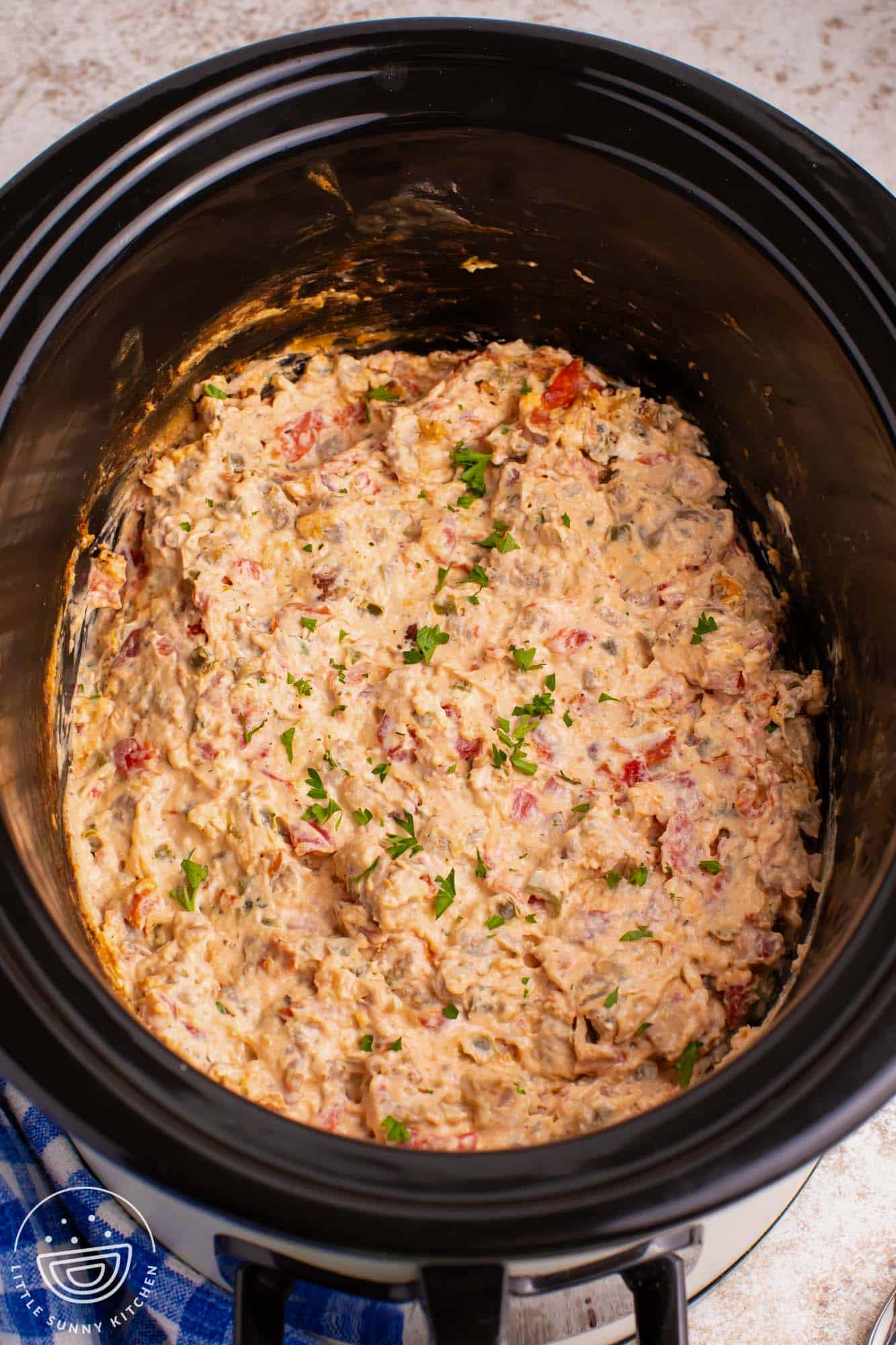 pizza dip in a black slow cooker.