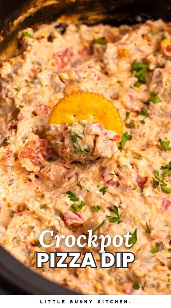 a pot of creamy dip with a cracker in it. Text overlay at bottom of image says "crockpot pizza dip"