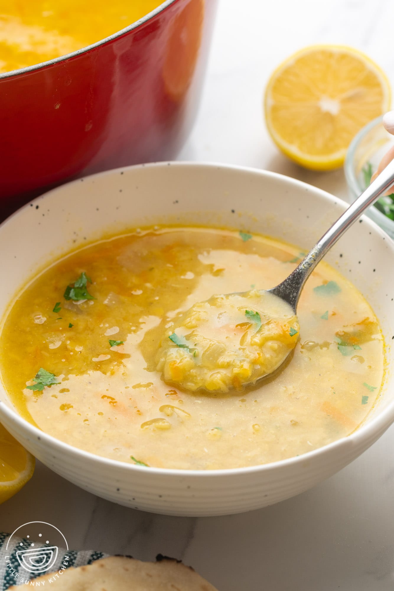 a bowl of yellow crushed lentil soup with a spoon