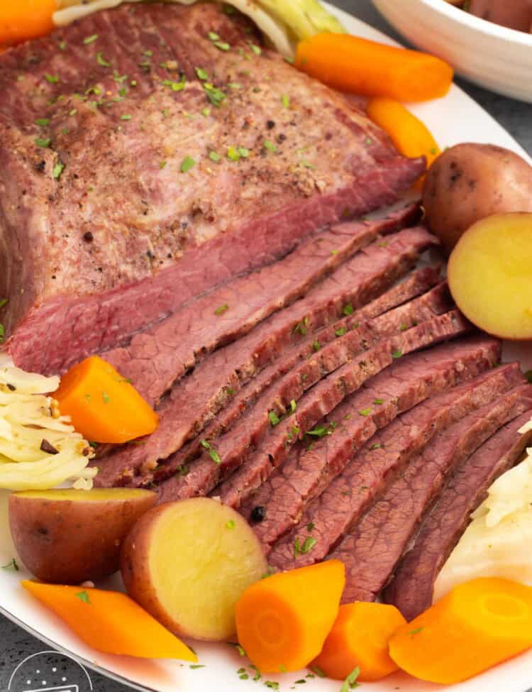 a platter of sliced corned beef with cabbage, carrots, and potatoes.