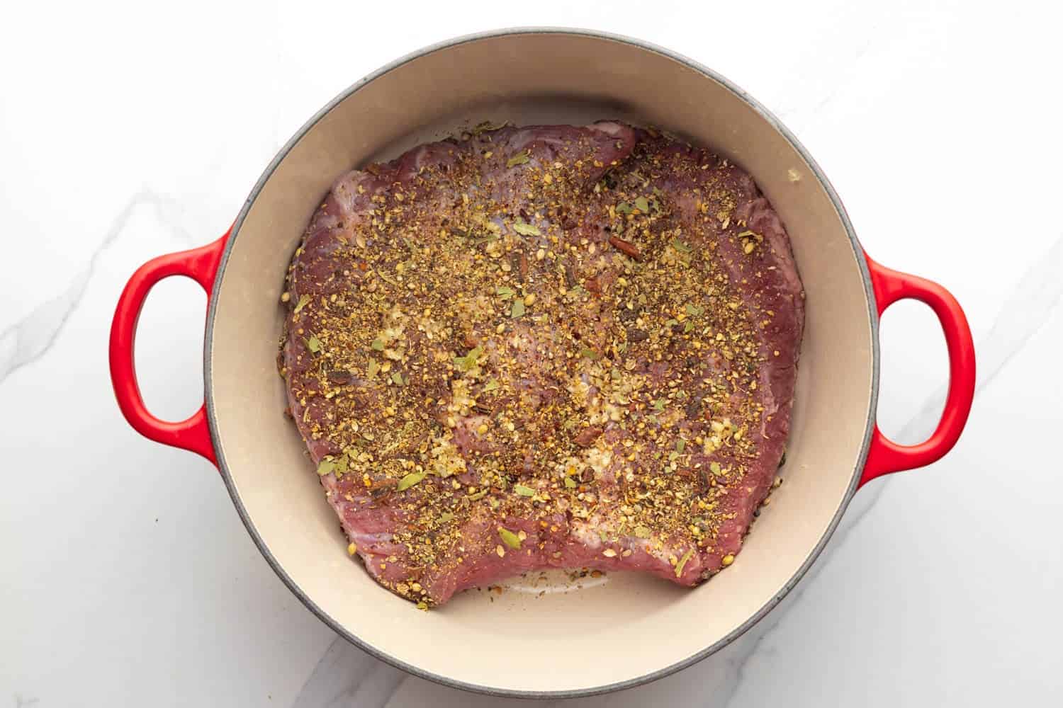 a whole corned beef brisket in a dutch oven with seasonings.