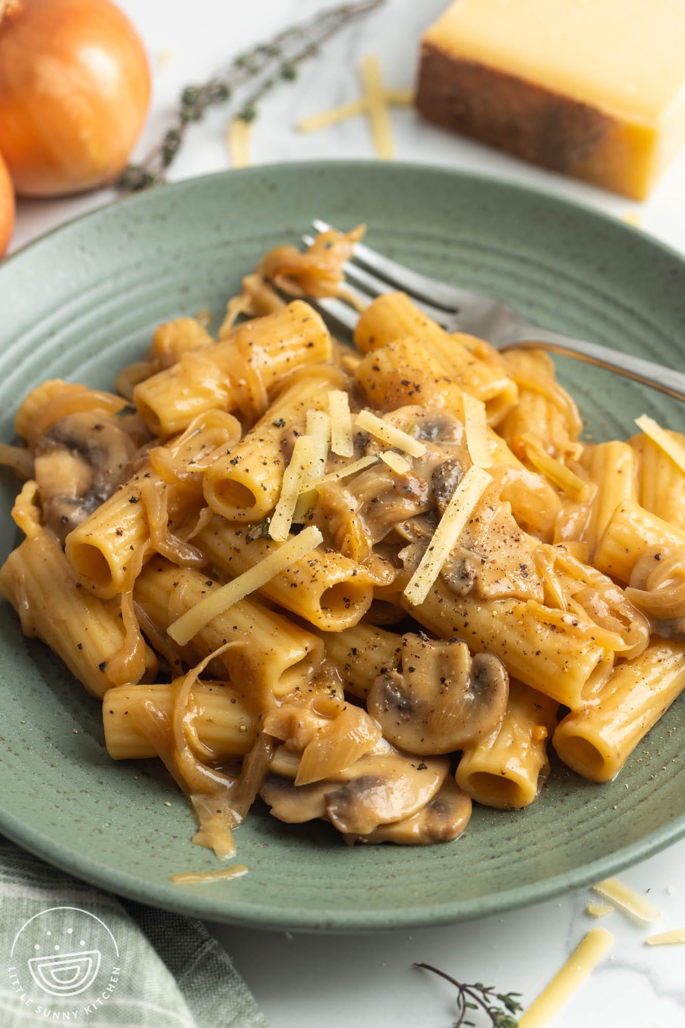 a green plate holding a serving of french onion pasta with mushrooms.
