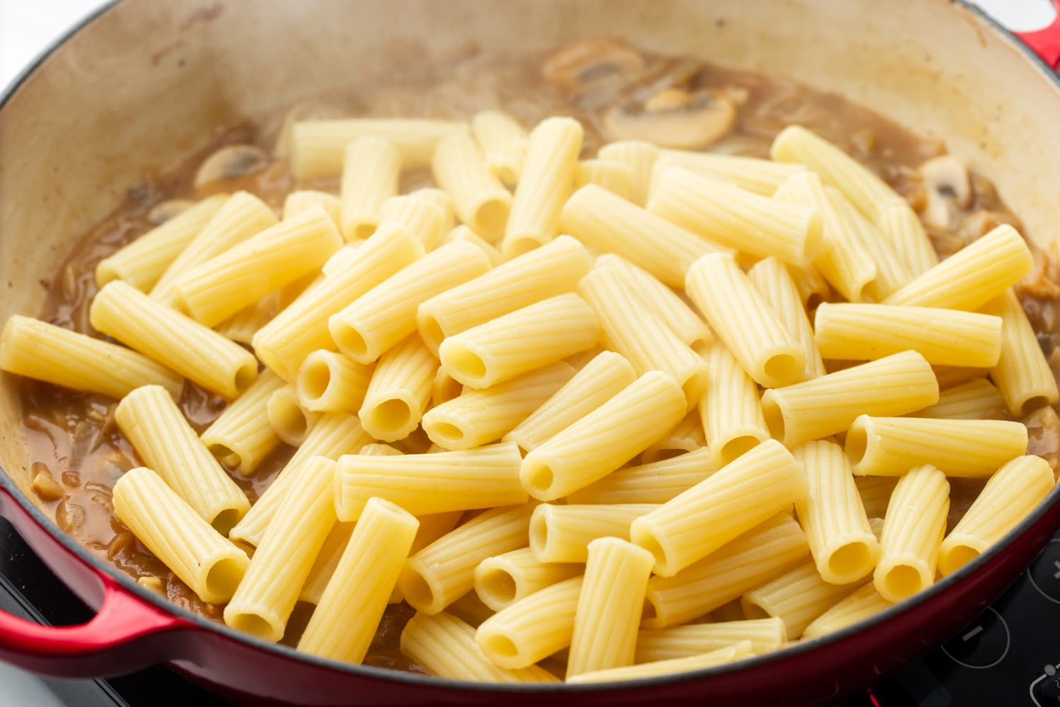 cooked rigatoni pasta added to pot of french onion pasta sauce.
