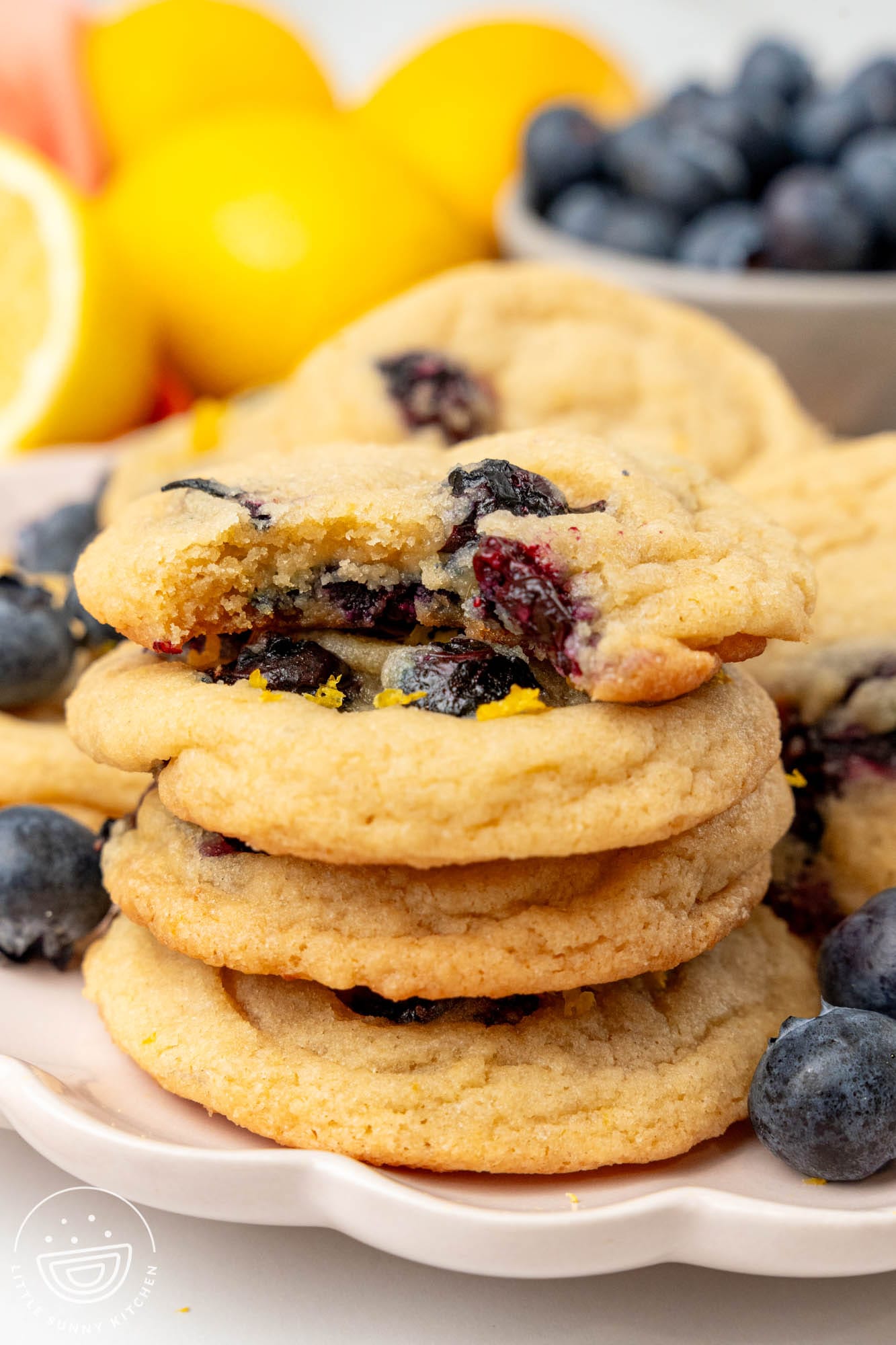 a stack of four lemon blueberry cookies. The top one has a bite taken.