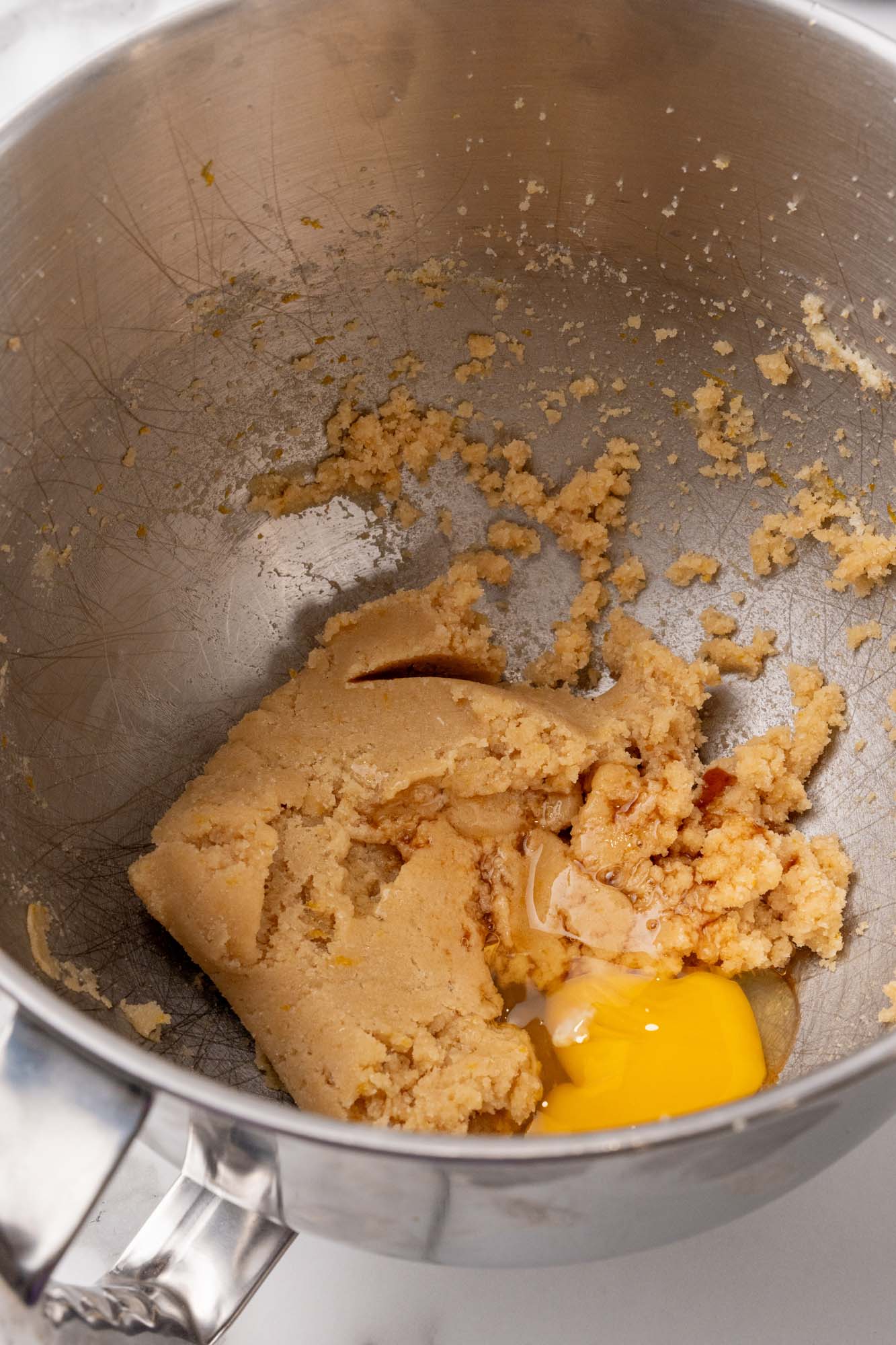 butter and brown sugar creamed together in a metal mixing bowl. An egg is added.