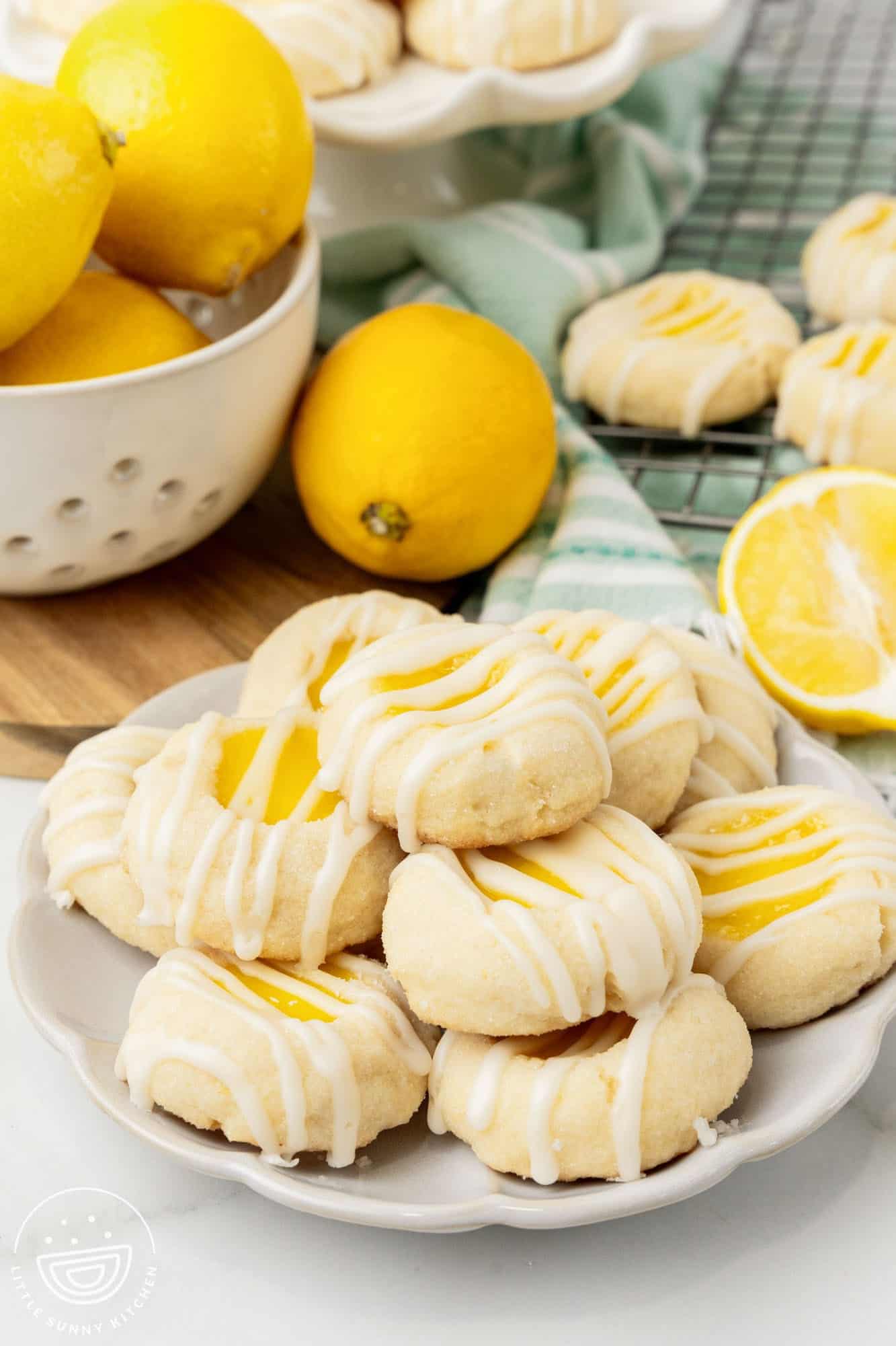 a plate of lemon curd cookies. Behind the cookies is a bowl of fresh lemons.