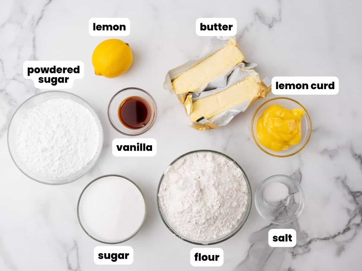 The ingredients for lemon curd cookies, measured into small bowls and arranged on a marble counter.