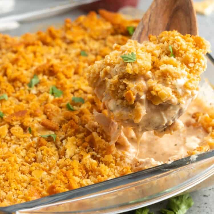 million dollar chicken casserole with crispy cracker topping, served with a wooden spoon.