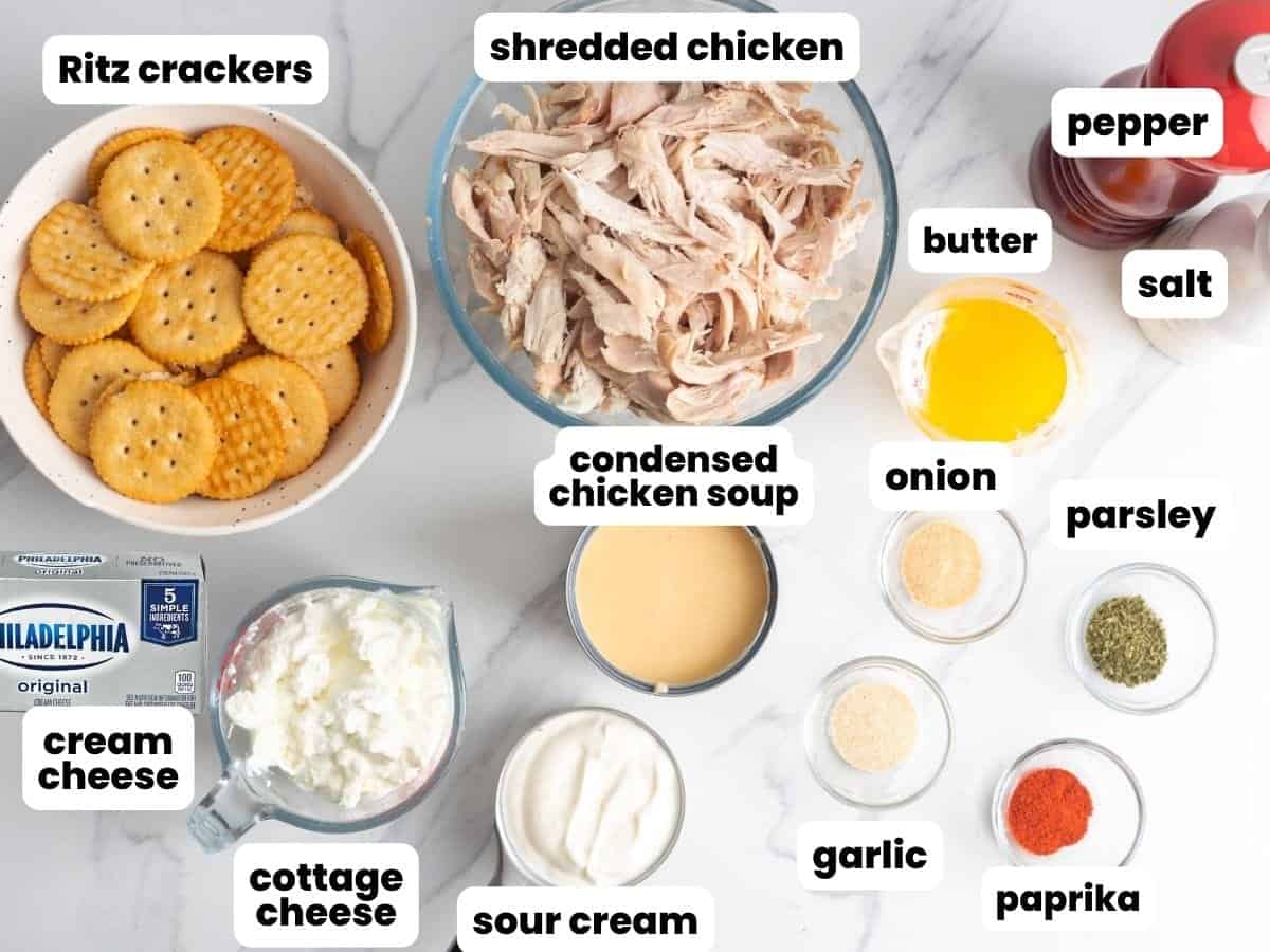 The ingredients for million dollar chicken casserole, including ritz crackers, shredded chicken, chicken soup, cream cheese, and seasonings.