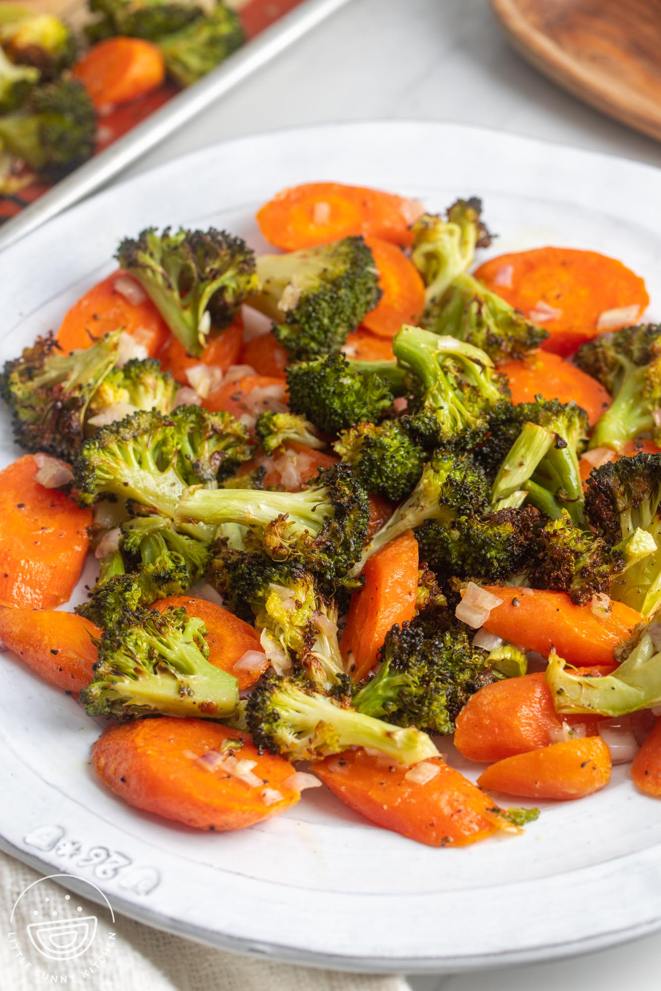 a white dinner plate with roasted sliced carrots and roasted broccoli .