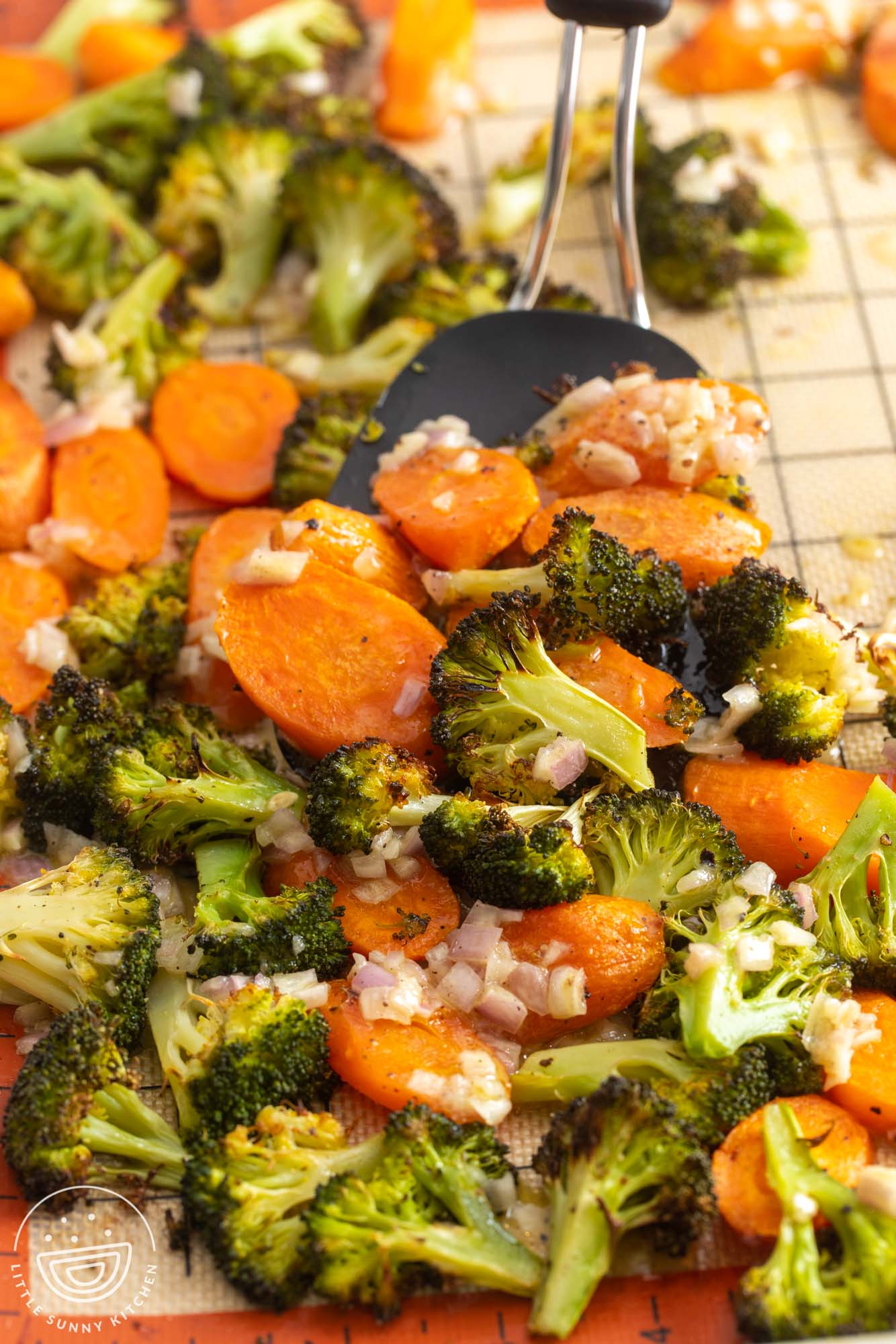 roasted broccoli and carrots with shallots on a gridded silpat, served with a spatula