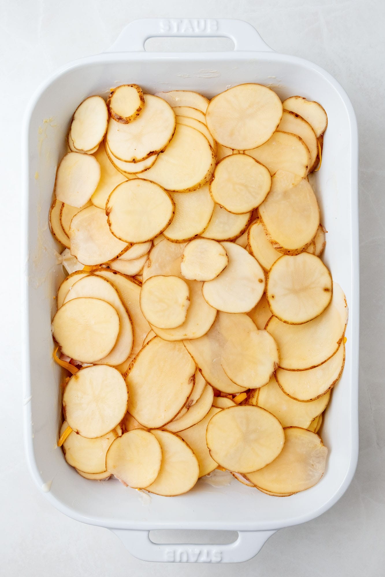 sliced potatoes in a casserole dish.
