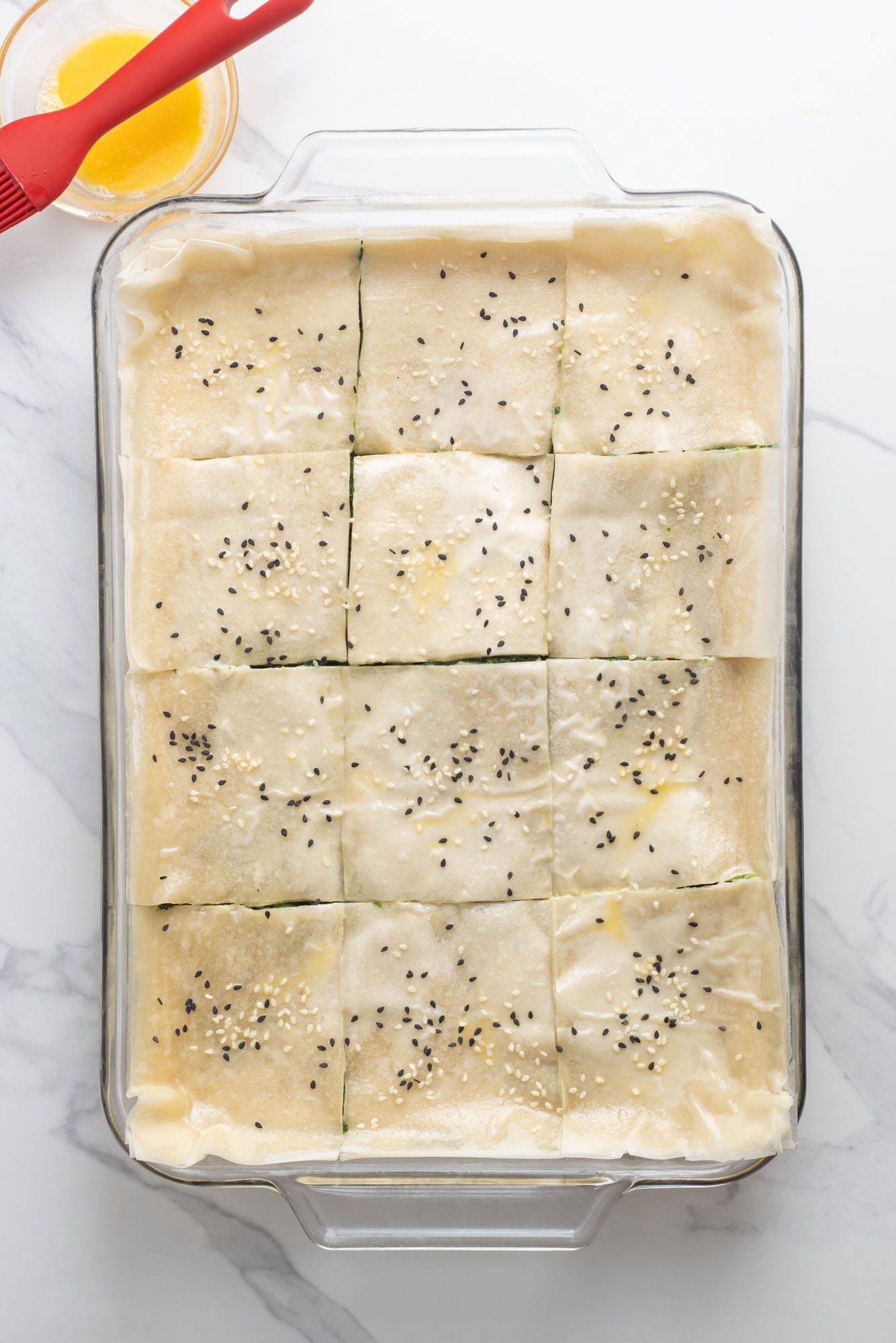 black and white sesame seeds on top of unbaked spanakopita