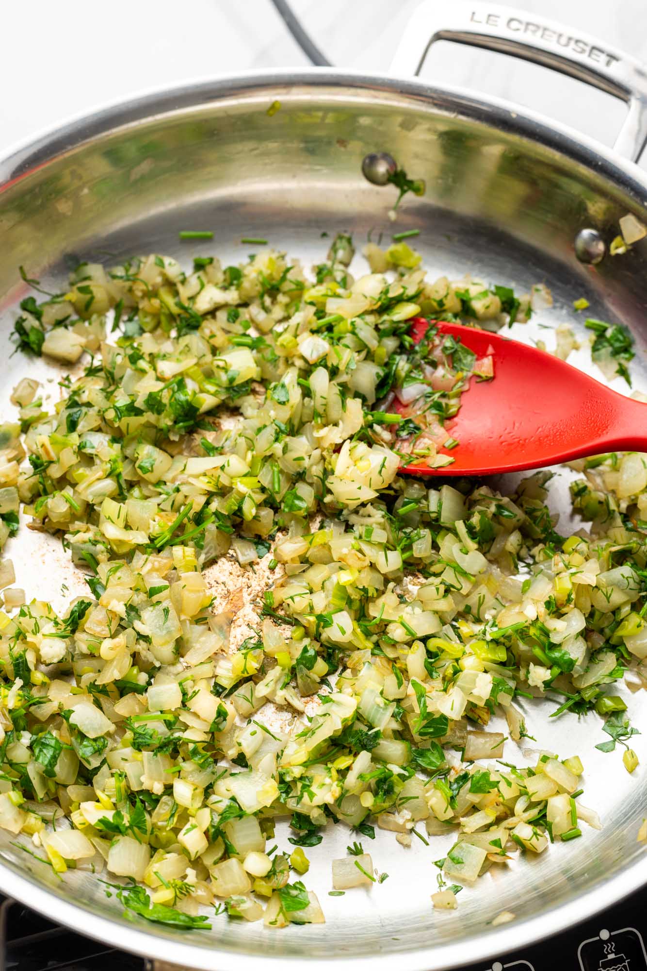sauteed onions and herbs for spanakopita in a skillet
