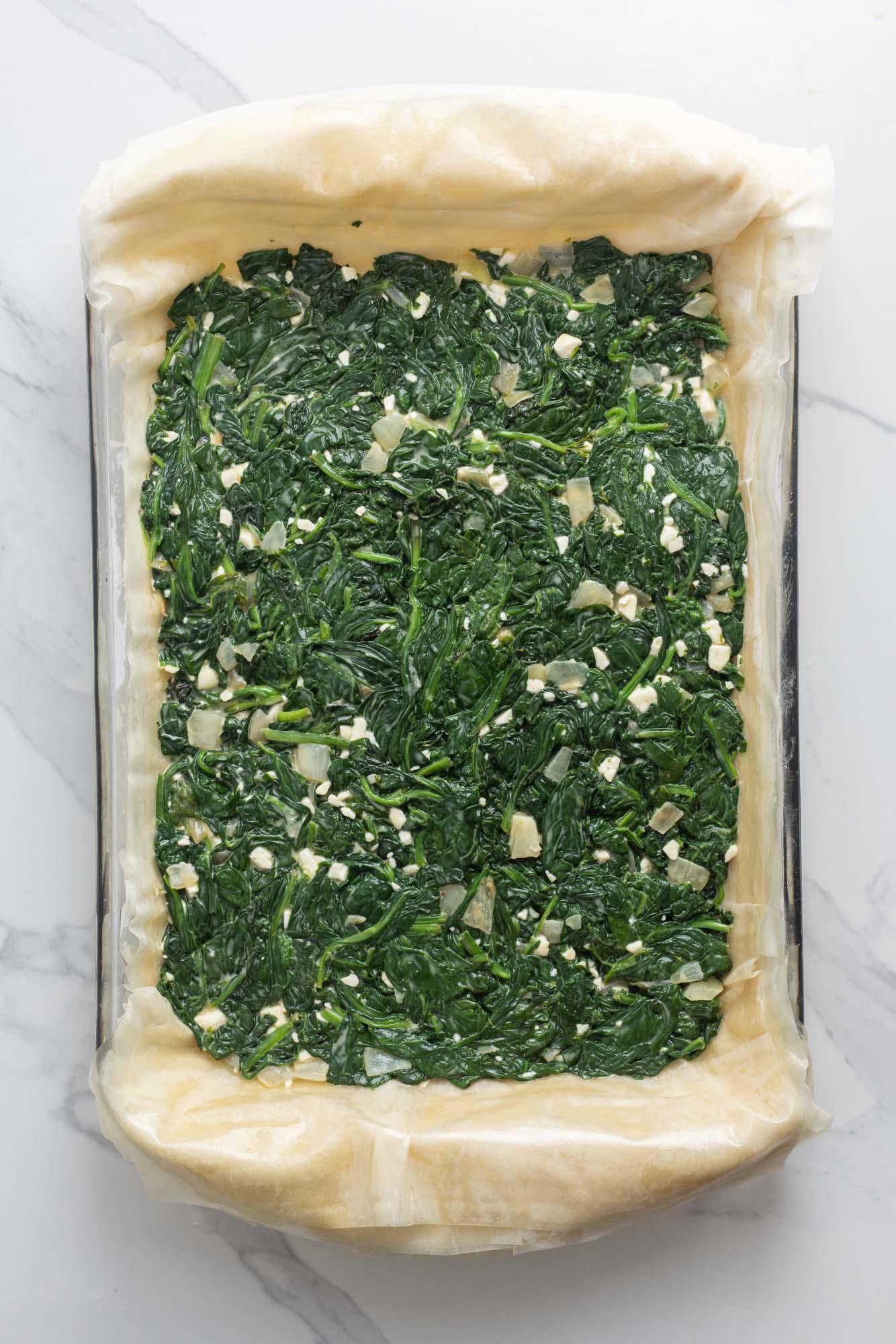 spinach filling added to filo dough in a 9x13 pan