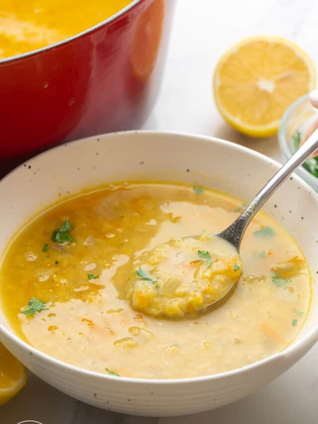 a bowl of yellow crushed lentil soup with a spoon