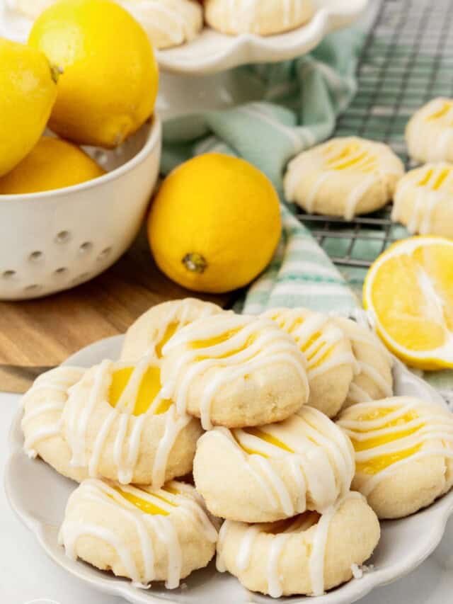 a plate of lemon curd cookies. Behind the cookies is a bowl of fresh lemons.