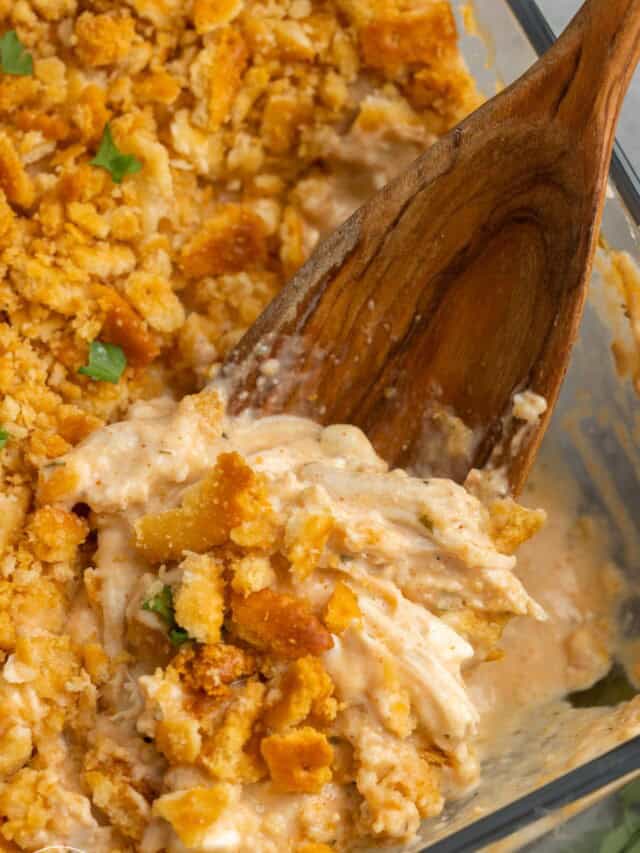 closeup of million dollar chicken casserole with a dark wooden spoon.
