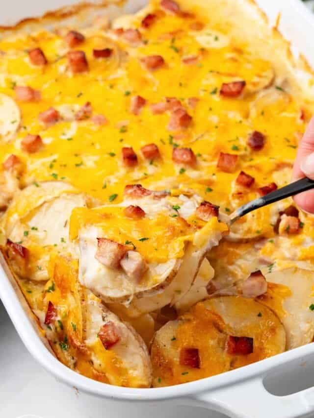 a white rectangular casserole of scalloped potatoes with ham.