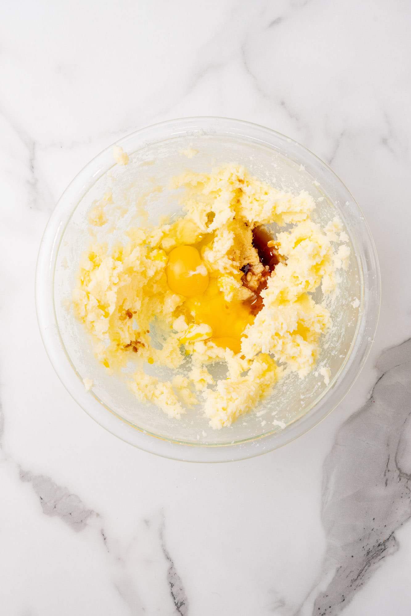 creamed butter and sugar with eggs and vanilla added to a glass bowl.