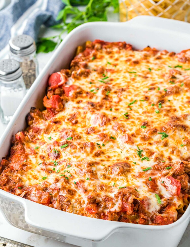 a large rectangular white baking dish filled with baked ziti with browned cheese on top