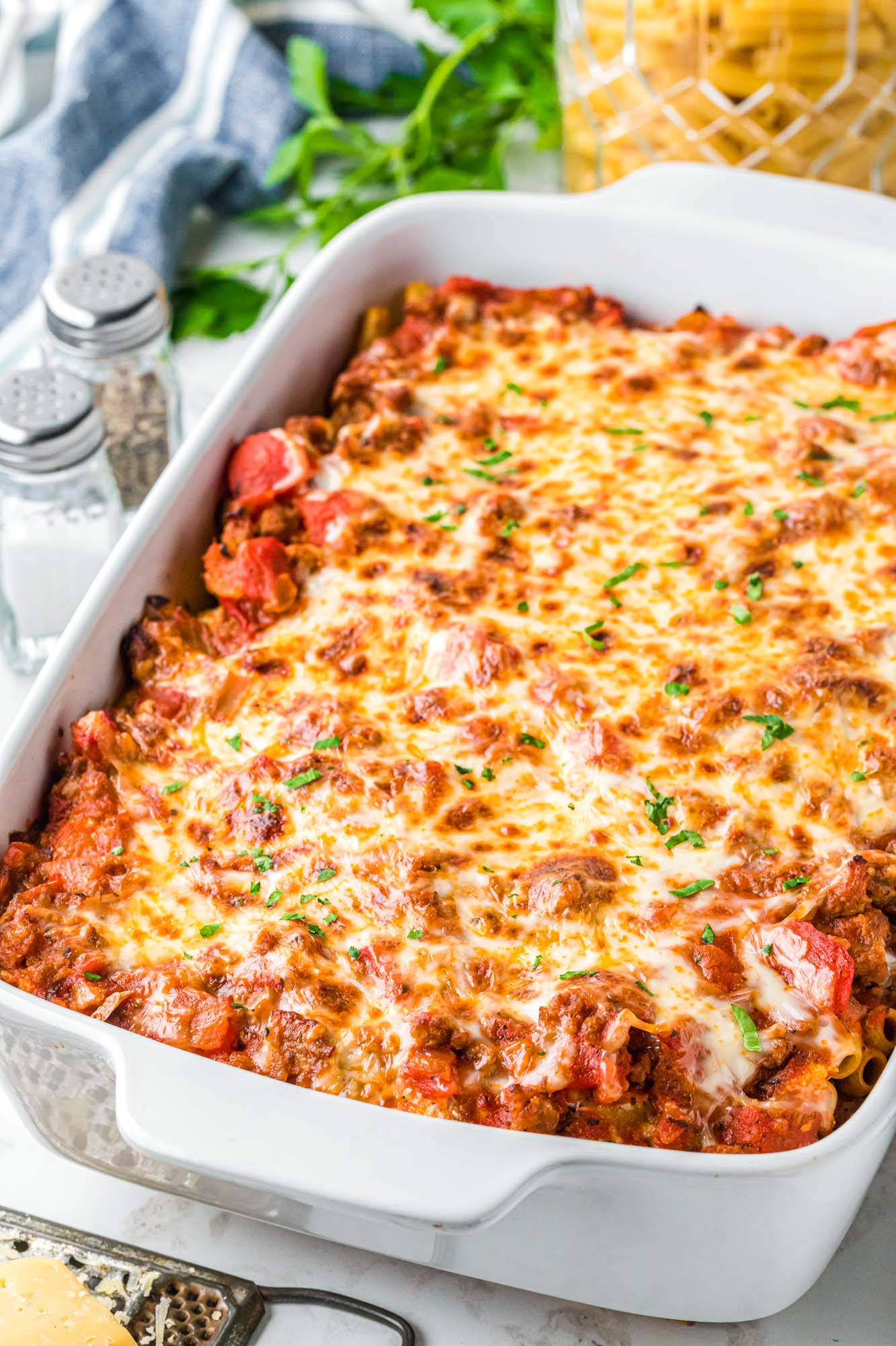 a large rectangular white baking dish filled with baked ziti with browned cheese on top