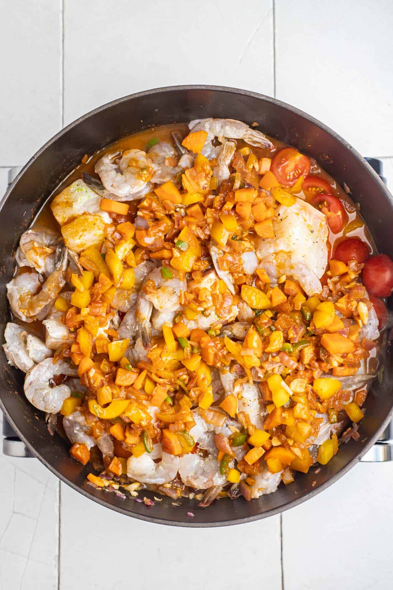 fish chunks and shrimp added to the pan to make Brazilian fish stew