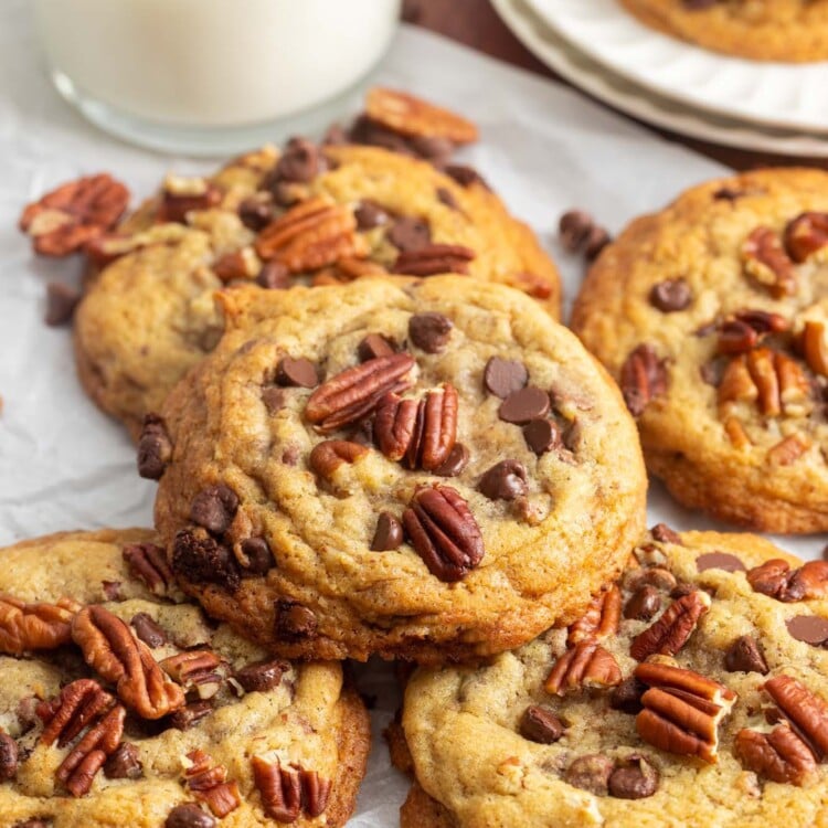 a stack of pecan chocolate chip cookies next to a glass of milk.