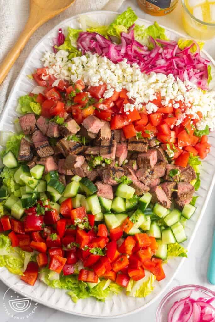 chopped flank steak salad with all of the ingredients chopped into cubes, arranged on a white platter.