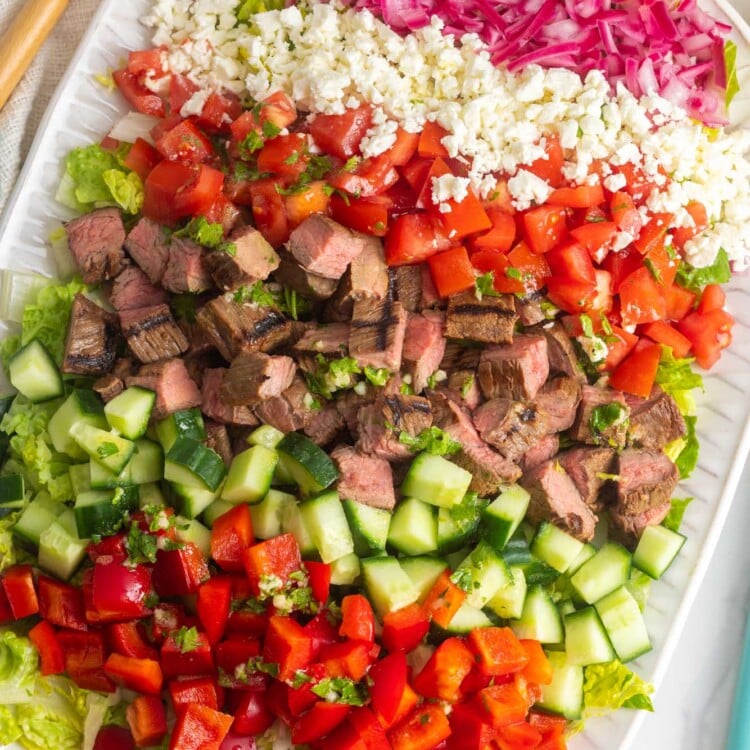 chopped flank steak salad with all of the ingredients chopped into cubes, arranged on a white platter.