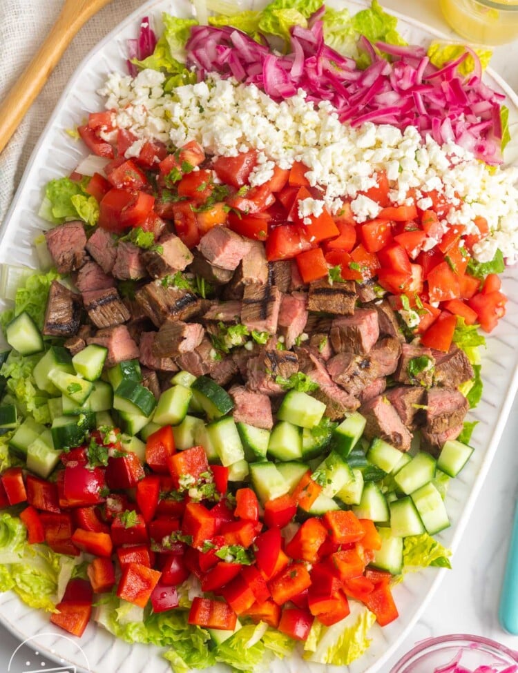 chopped flank steak salad with all of the ingredients chopped into cubes, arranged on a white platter.