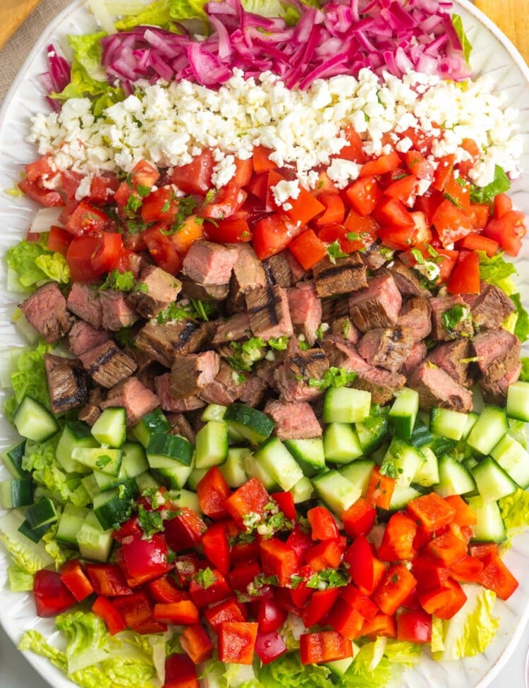 a rectangular platter holding a chopped flank steak salad, arranged in stripes.