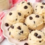 balls of cottage cheese cookie dough with chocolate chips on a fluted ceramic plate next to a red and white plaid napkin.