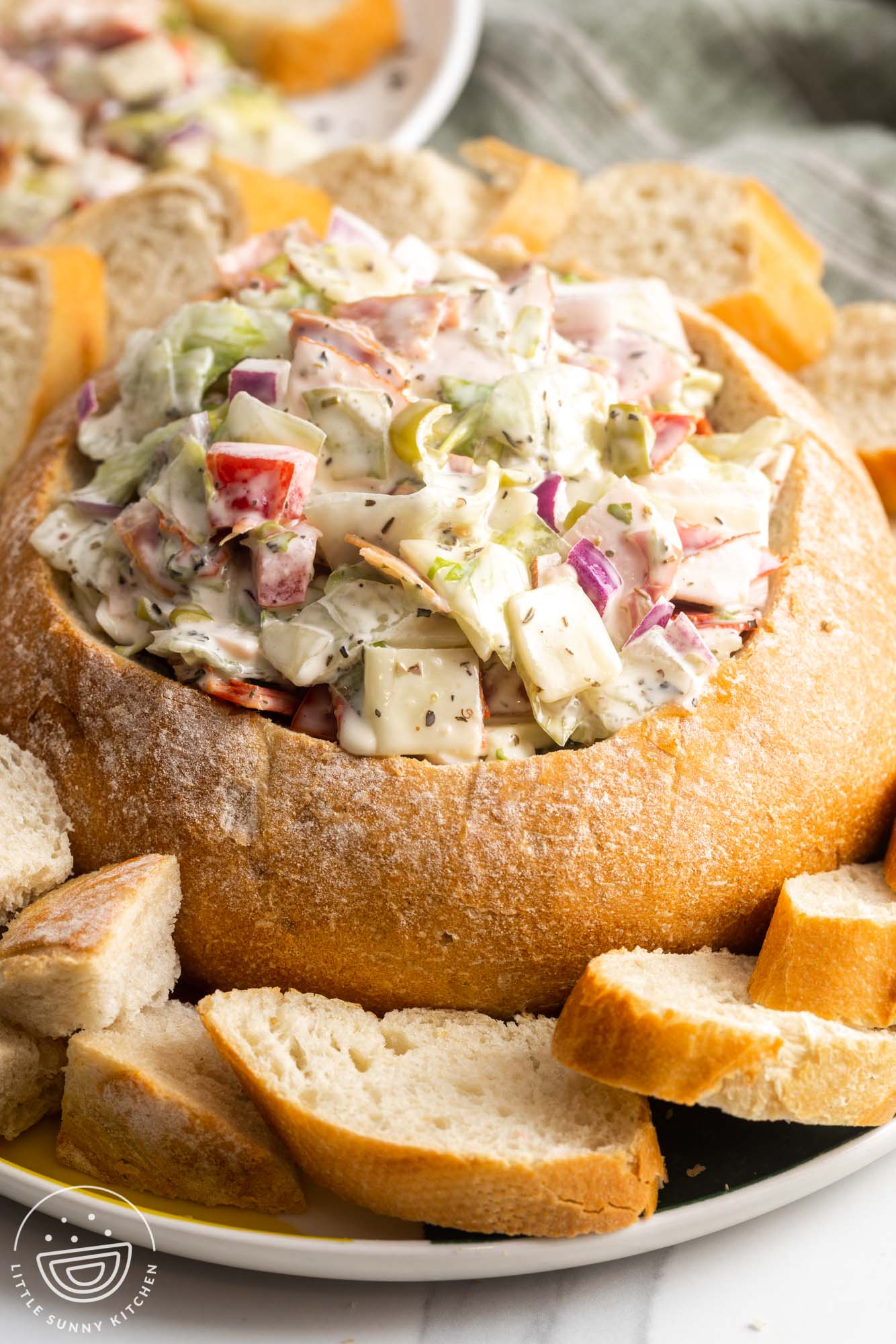 a platter of sliced bread. In the center is a large bread bowl filled with Italian Hoagie Dip.