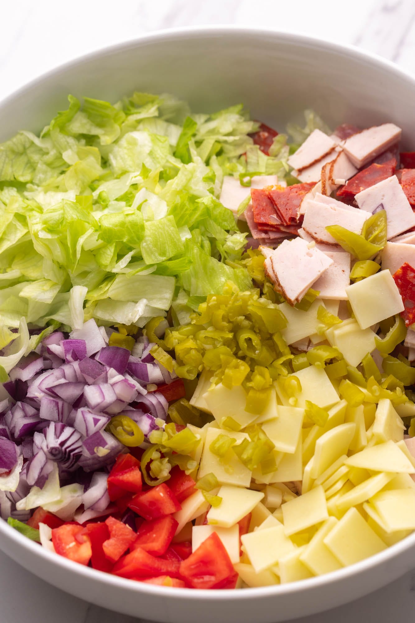 chopped Italian hoagie dip ingredients added to a large bowl.