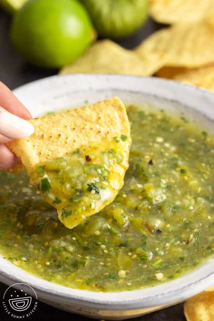 Dipping a tortilla chip in a bowl of salsa verde