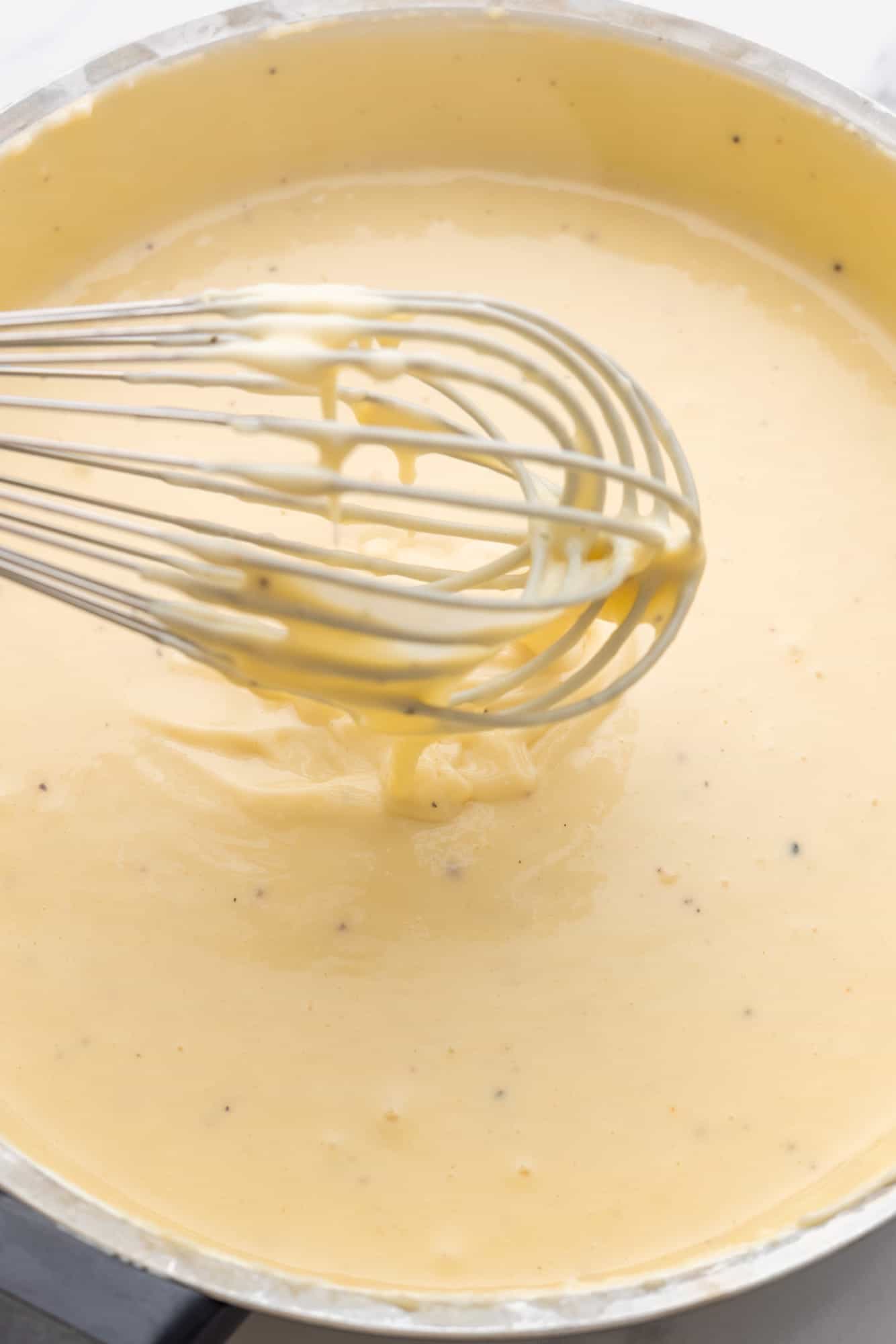 creamy bechamel sauce in a pan with a whisk. 