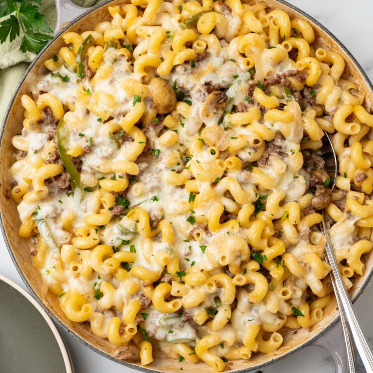 overhead view of a large skillet of macaroni with steak, cheese, peppers, onions, and mushrooms.