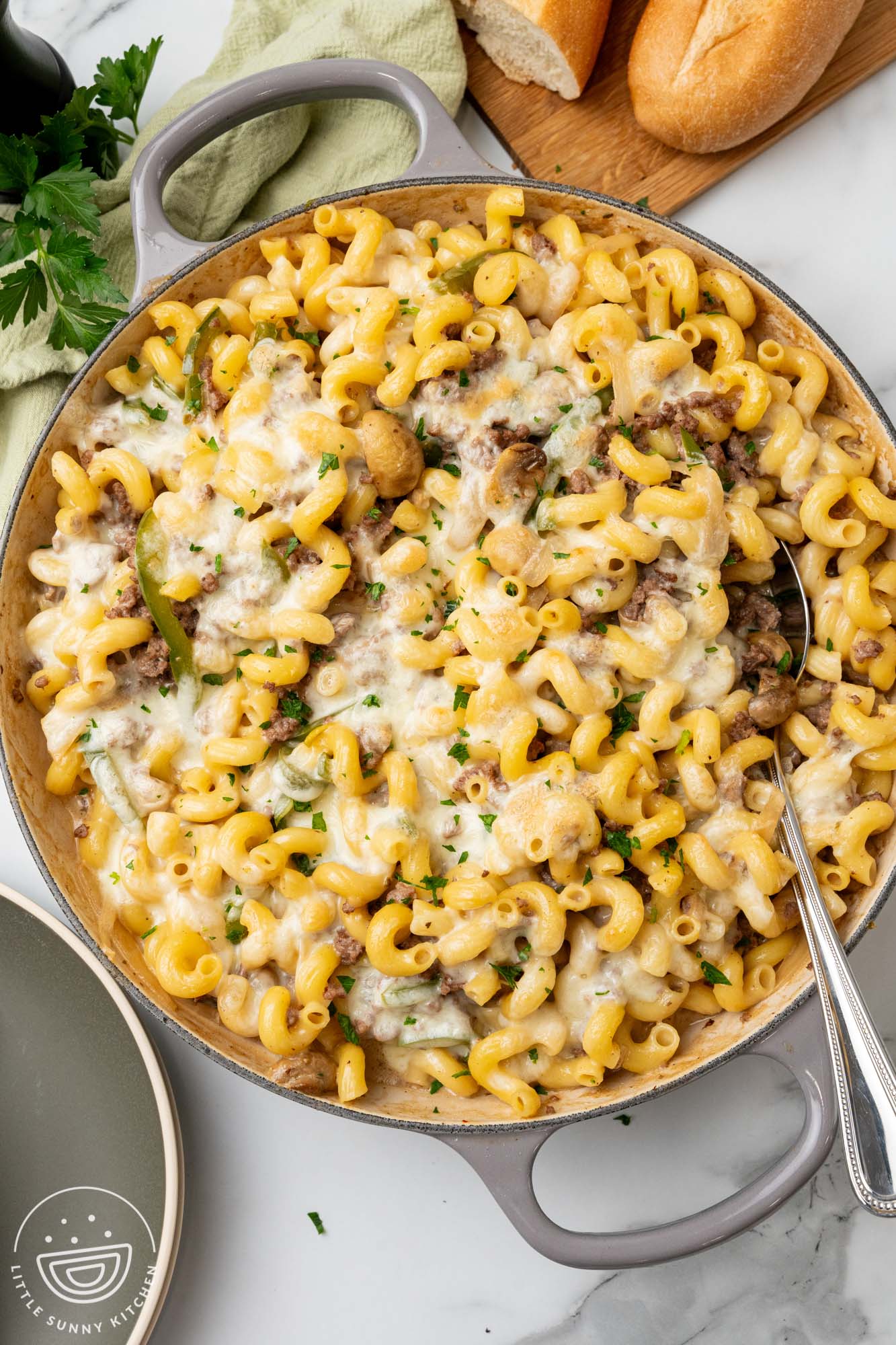 overhead view of a large skillet of macaroni with steak, cheese, peppers, onions, and mushrooms.