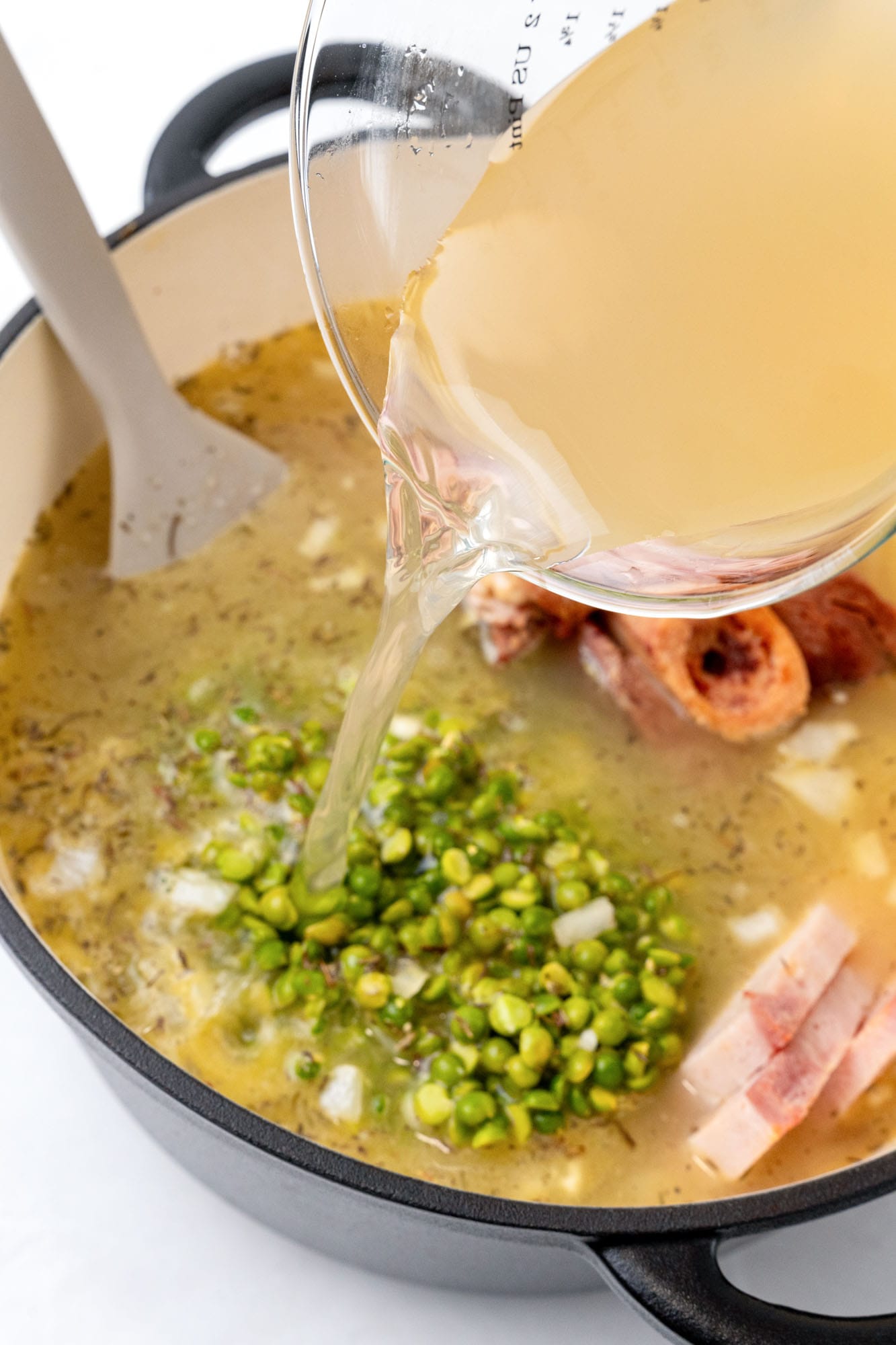 Broth poured into a dutch oven with ham bone and green split peas.