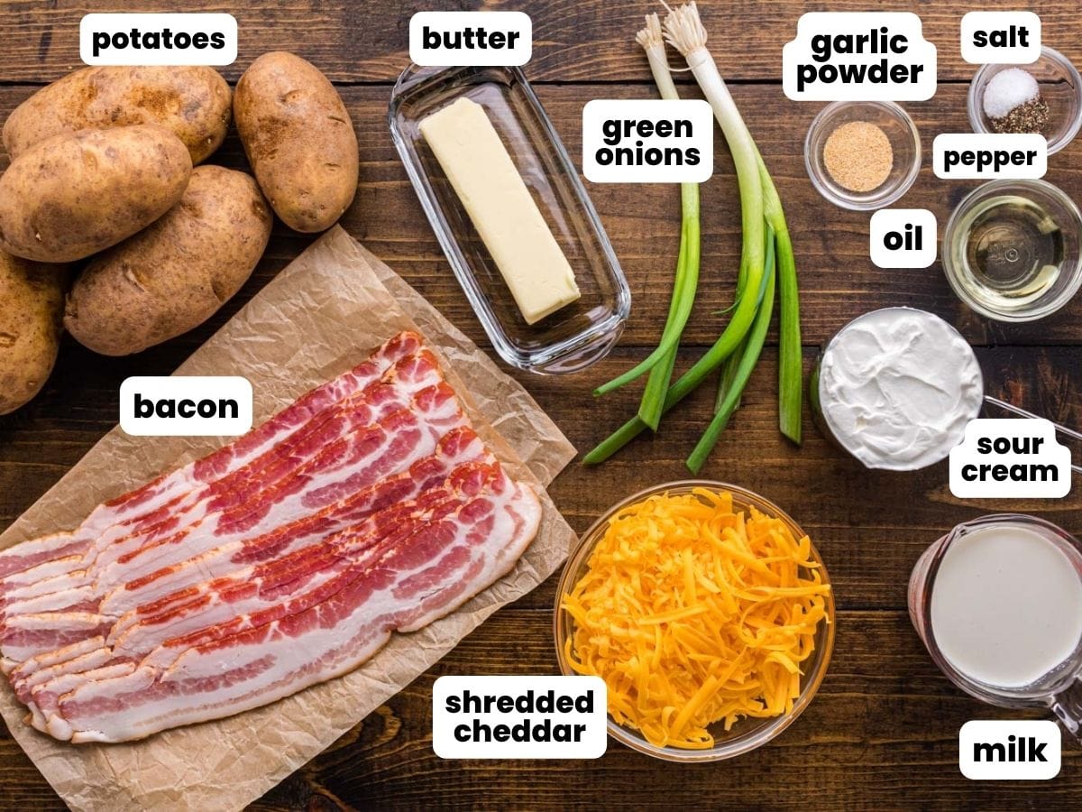potatoes, bacon, cheese, and other ingredients arranged on a dark wooden surface. 