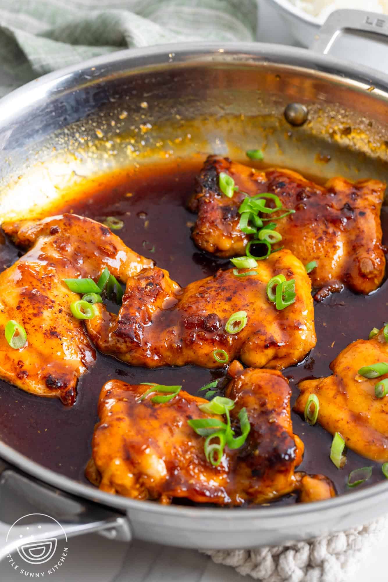 Five boneless chicken thighs in a skillet with apricot glaze.