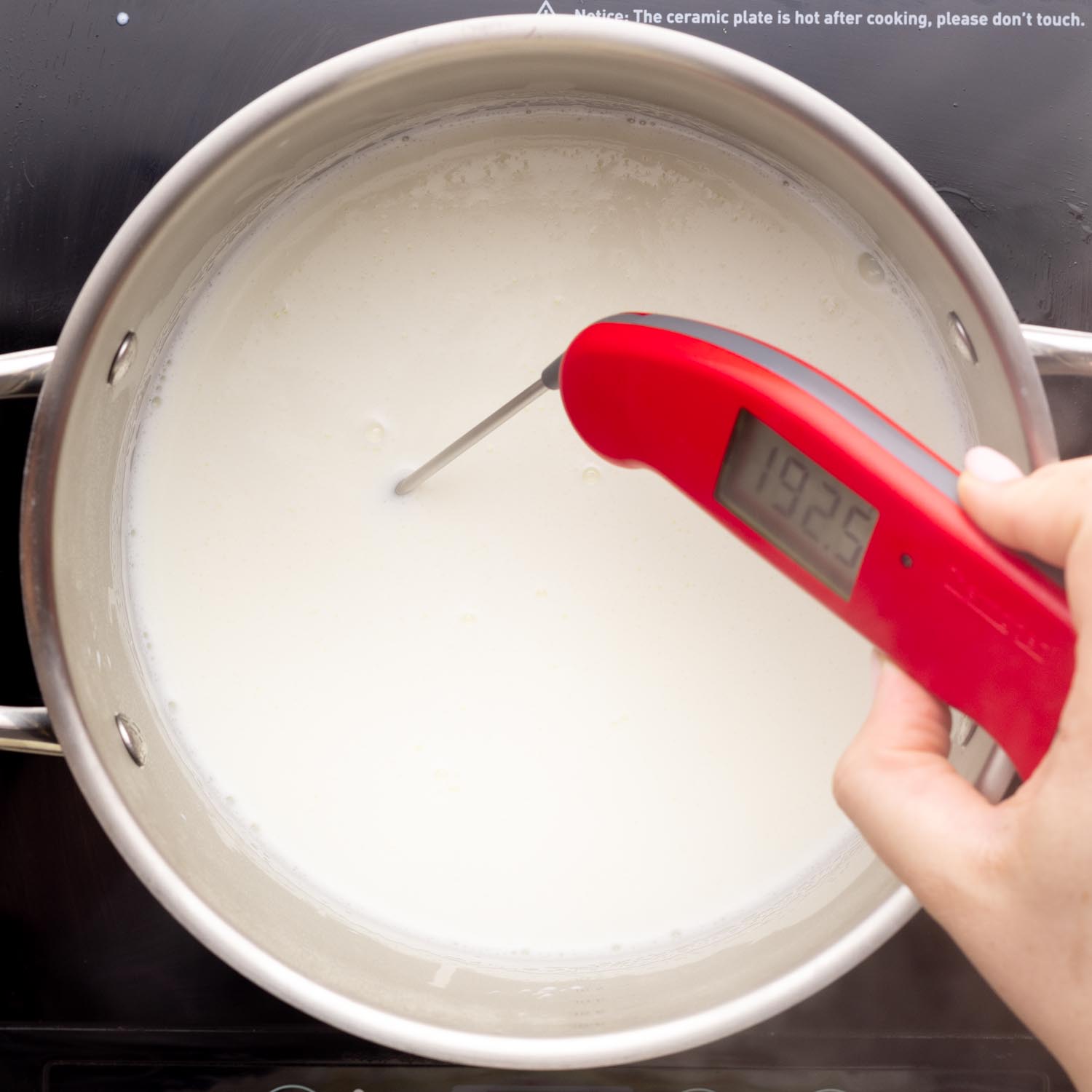 Taking the temperature of milk in a pot using a red thermapen
