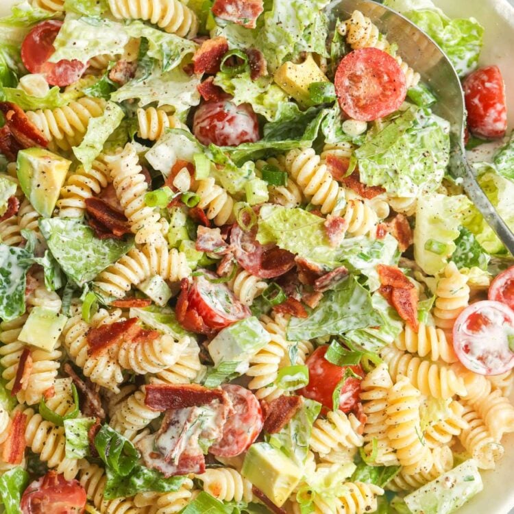 a large white serving bowl of homemade BLT pasta salad with lettuce, cherry tomatoes, and rotini pasta