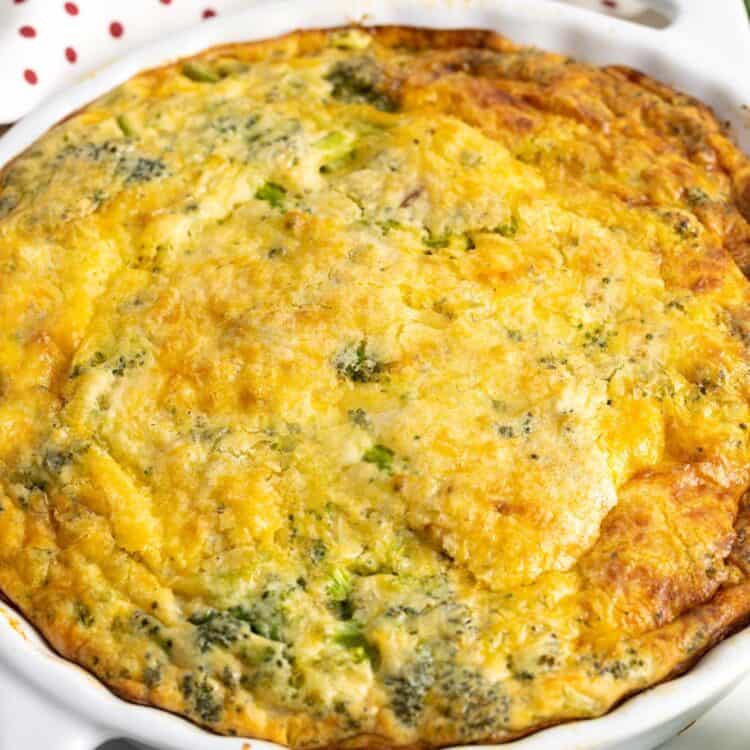 a round ceramic pie dish holding baked bisquick quiche with broccoli.