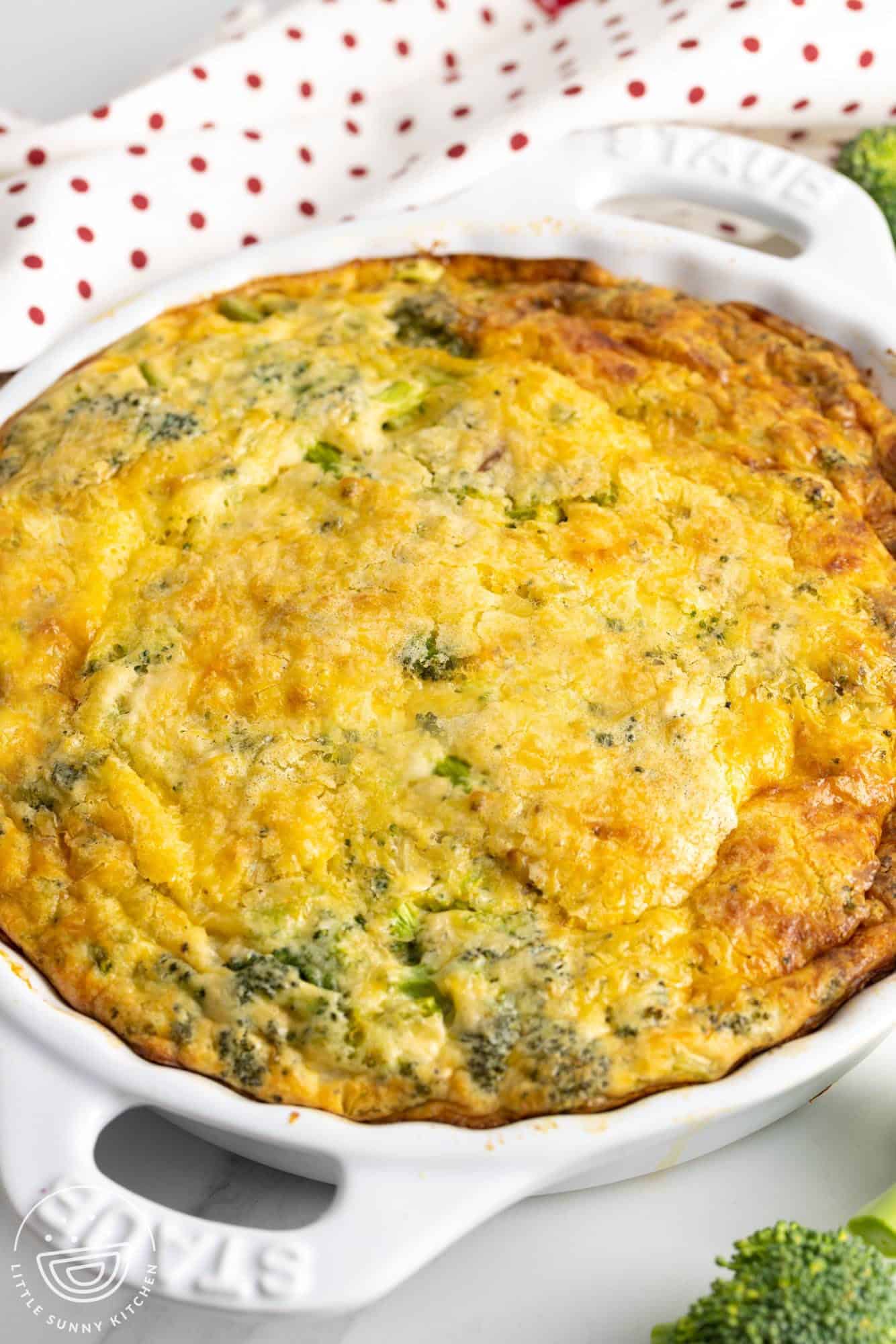 a round ceramic pie dish holding baked bisquick quiche with broccoli.