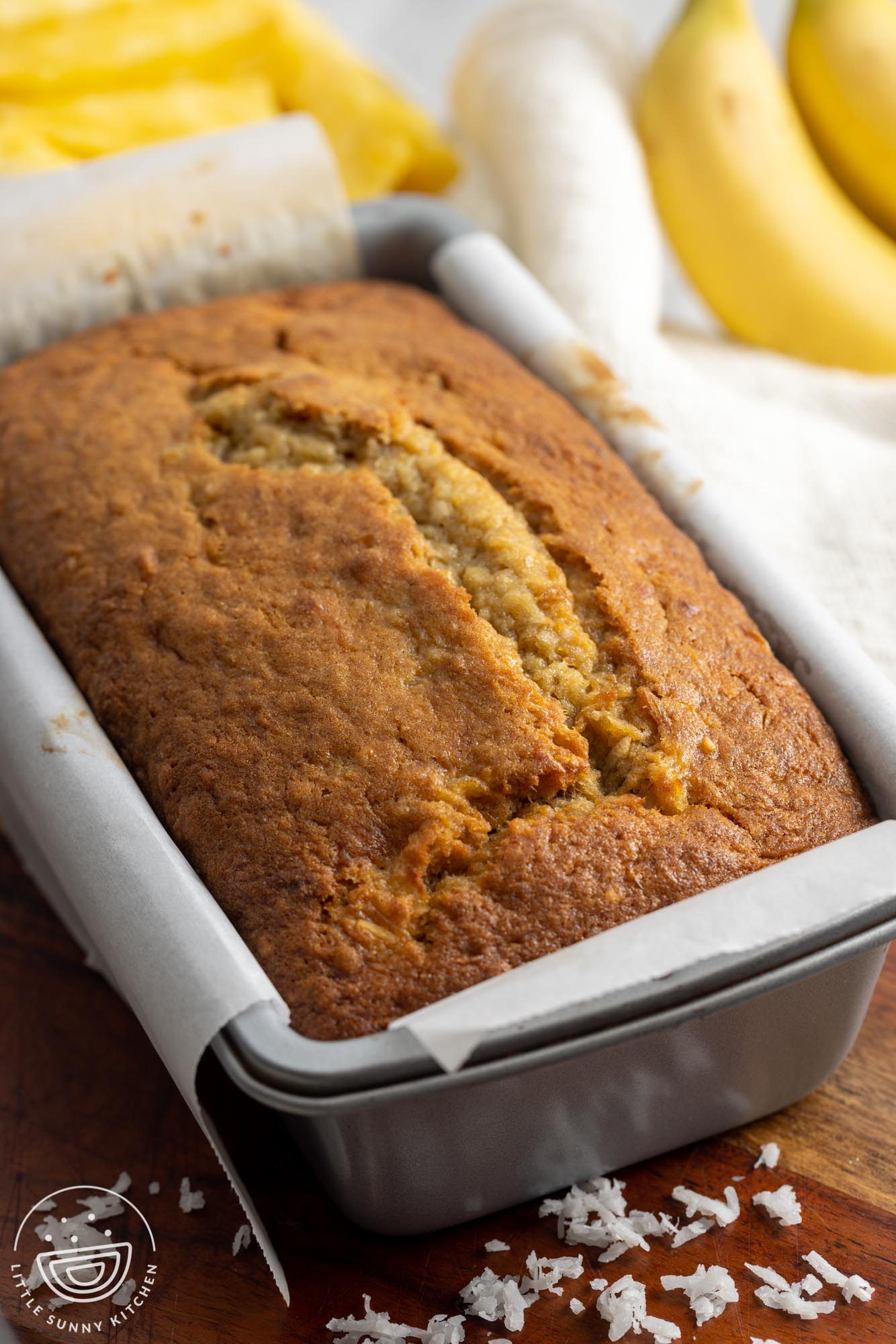 Baked banana bread in a loaf pan lined with parchment paper.
