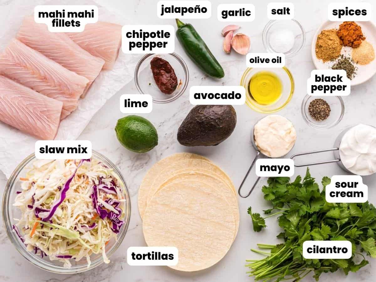 The ingredients for mahi mahi grilled tacos with creamy slaw, arranged on a marble counter.