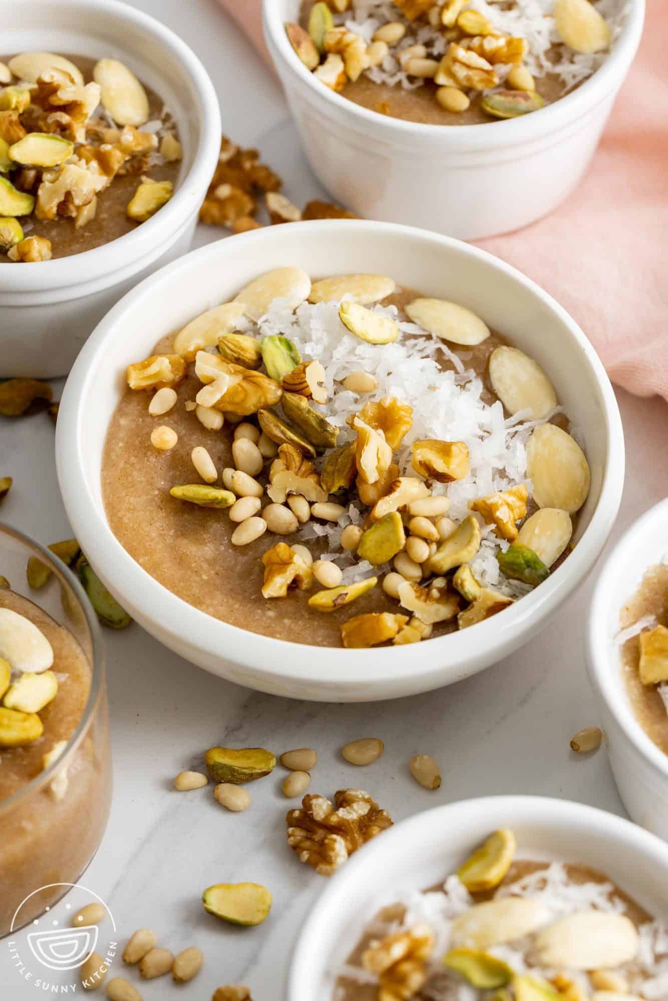 Meghli caraway pudding served in small white bowls, topped with coconut and nuts