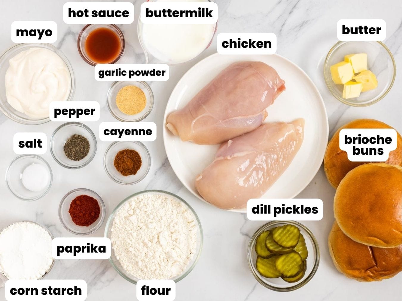 Ingredients needed to make crispy popeye's chicken sandwiches including chicken, flour, cornstarch, brioche buns, butter, mayo, hot sauce, pickles, and seasonings.